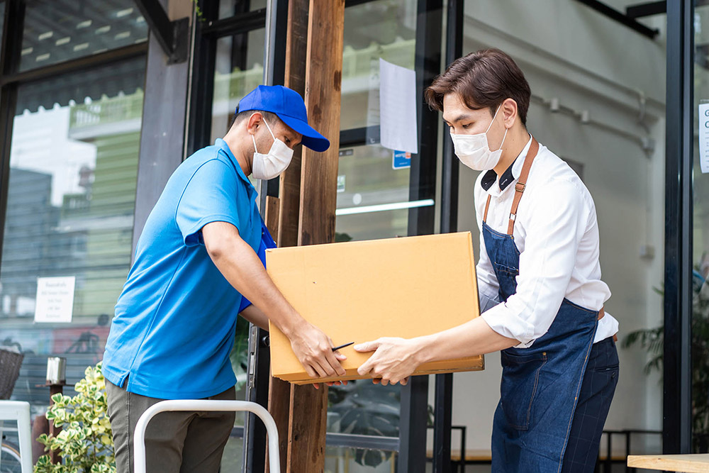 Delivery person handing package to cafe worker