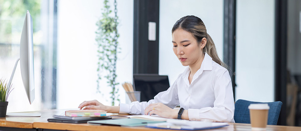 Asian businesswoman using calculator and laptop.