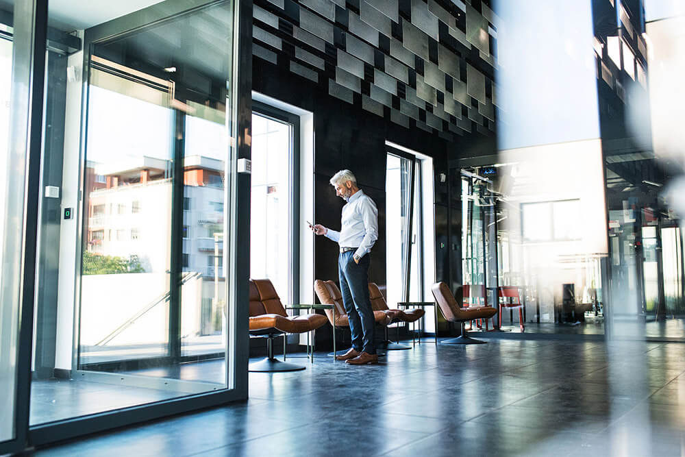 Mature businessman with smartphone in office.